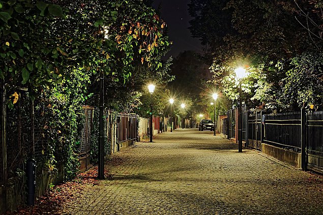 Night view of a serene cobblestone street in Warsaw, evoking the tranquility of the city's residential areas for a stay.
